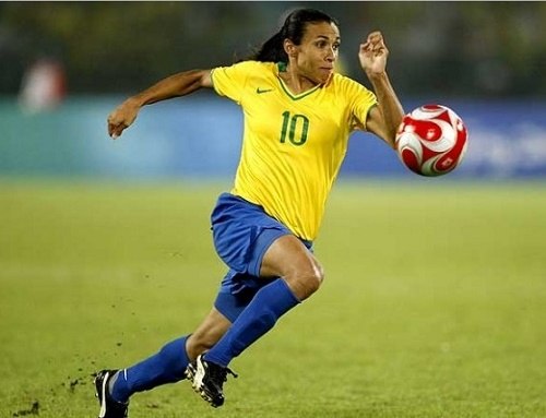 Woman playing soccer in a yellow shirt and blue shorts