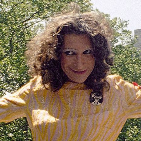 Woman with curly brown hair and a yellow striped dress