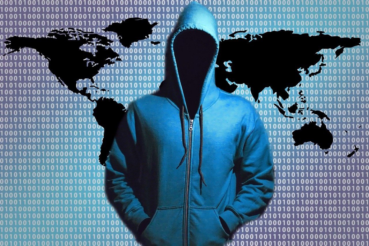 artistic image with a hooded, faceless figure in front of binary code and an abstracted global map