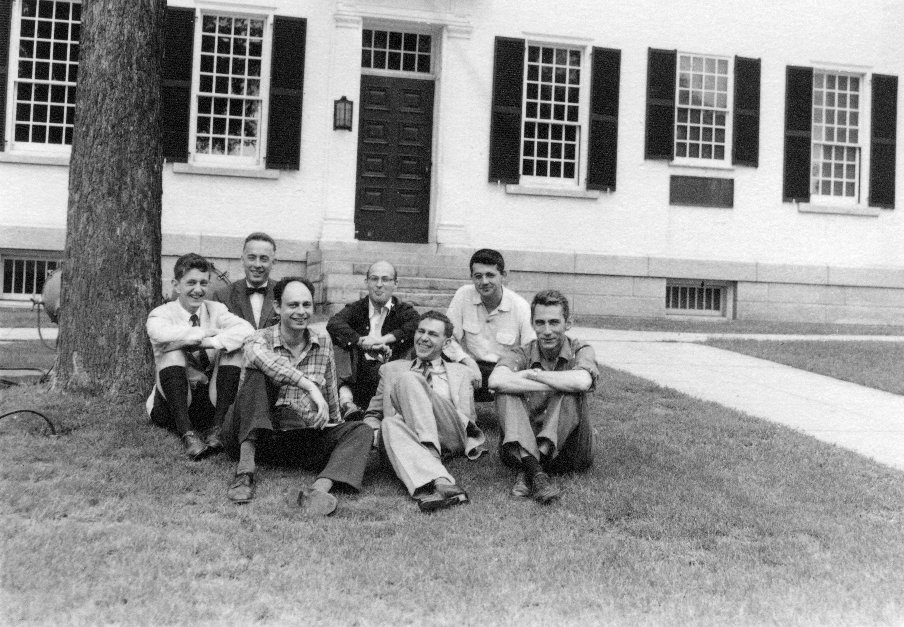 Black and white photo of several men in front of a white building
